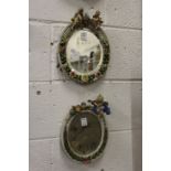 A pair of continental floral encrusted oval porcelain mirrors.