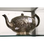 A Victorian silver teapot with embossed decoration.