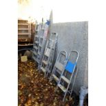 A quantity of aluminium step ladders and extending ladders.