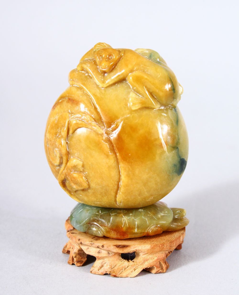 A GOOD CHINESE CARVED JADE MONKEY, PEACH & LOTUS SNUFF BOTTLE AND STAND - the upper part carved with