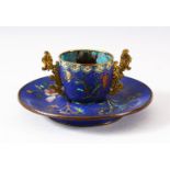A CHINESE CLOISONNE TWIN HANDLE CUP AND SAUCER, decorated with floral sprays upon a geometric