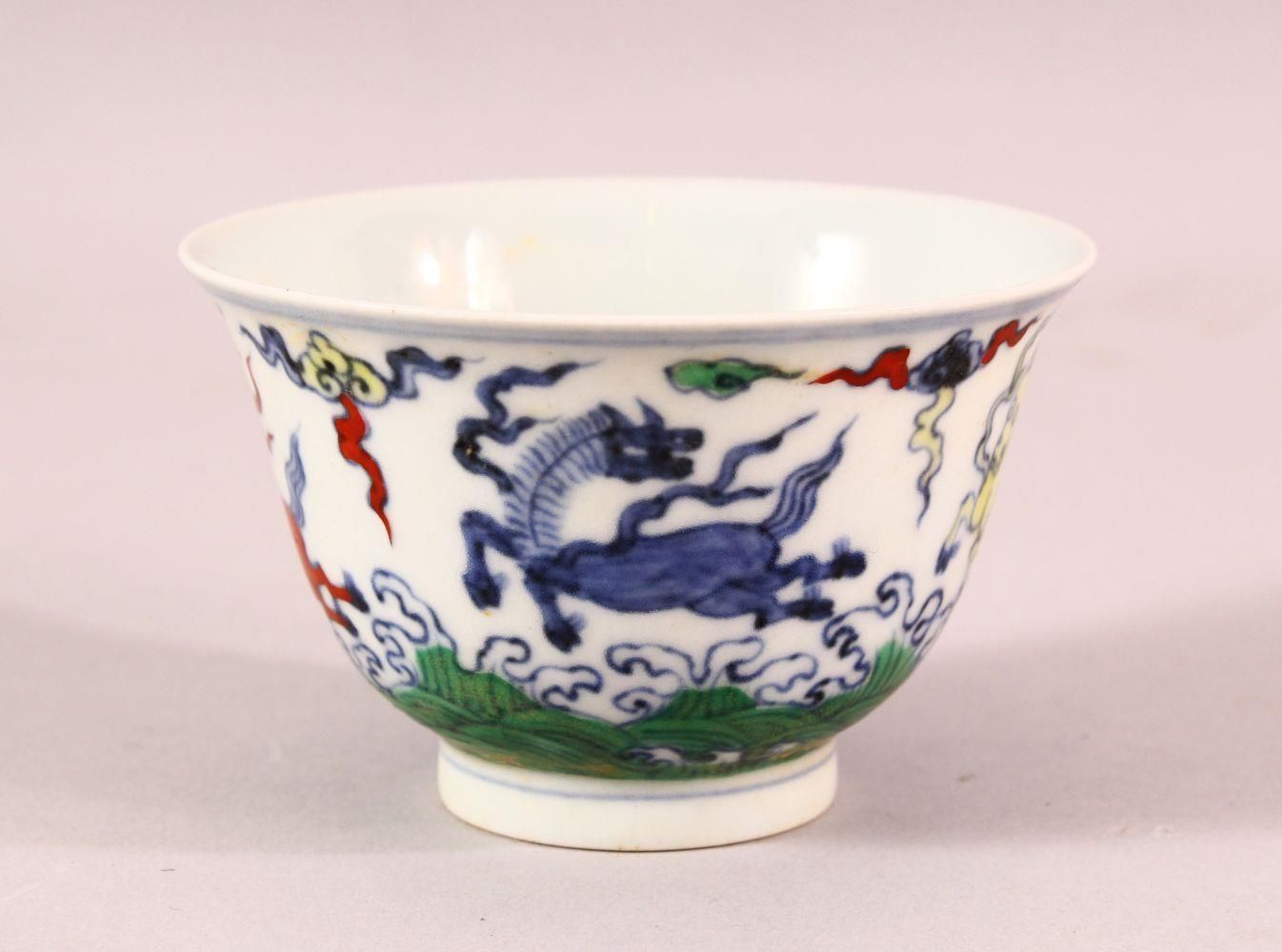 A CHINESE DOUCAI PORCELAIN HORSE CUP - depicting four horses amongst clouds, the base with a 6