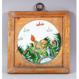 A CHINESE FAMILLE VERTE FRAMED PORCELAIN PANEL - the plaque depicting a kylin amongst foliage -