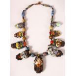AN USUAL AFGHAN MULTICOLOURED GLASS NECKLACE, the pendant drops modelled as human faces,