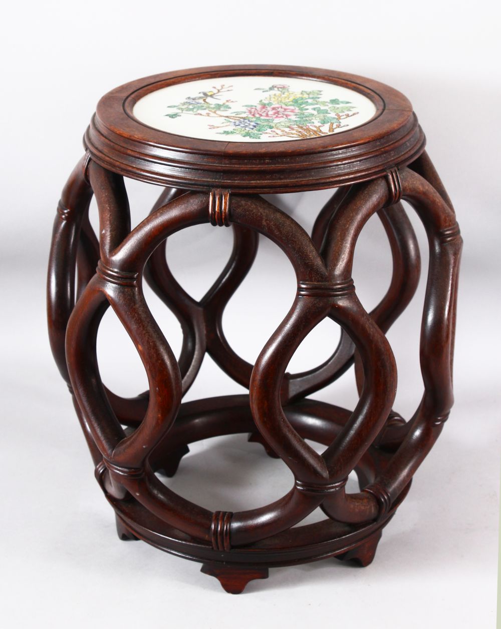 A CHINESE CARVED HARDWOOD BARREl TABLE WITH PORCELAIN FAMILLE ROSE INSET PANEL - the carved open