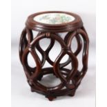 A CHINESE CARVED HARDWOOD BARREl TABLE WITH PORCELAIN FAMILLE ROSE INSET PANEL - the carved open