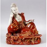 A CHINESE COPPER RED GLAZED PORCELAIN FIGURE OF GUANYIN - guanyin leaning upon a lion dog - the