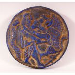 A CIRCLUAR LAPIS TABLET, carved with a male figure, lion and snake, 14cm diameter.