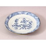 A SMALL 18TH CENTURY KANGXI BATAVIAN BLUE AND WHITE SAUCER, with floral decoration, 12cm diameter.