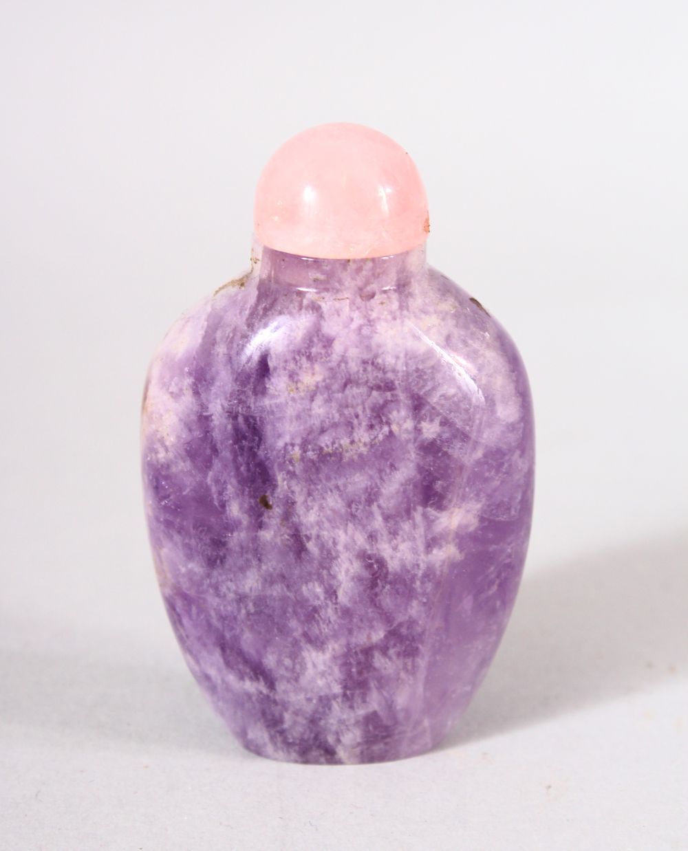 A CHINESE CARVED AMETHYST SNUFF BOTTLE - with a pink stone stopper, 7cm