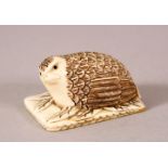 A JAPANESE CARVED IVORY NETSUKE OF A RECUMBENT QUAIL - seated upon stylized leaf, signed underside