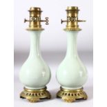 A PAIR OF CELADON PORCELAIN VASES CONVERTED TO LAMPS with brass mounts, 40cm high.