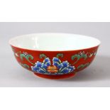 A CHINESE RED GROUND PORCELAIN BOWL, the exterior painted with blue flowers and foliate