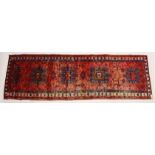 A PERSIAN HEIRZ RUNNER, red ground with four large medallions (some wear). 10ft 4ins x 3ft 3ins.