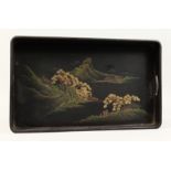 A JAPANESE BLACK LACQUER TWIN HANDLED TRAY decorated with a mountainous river landscape. 17ins