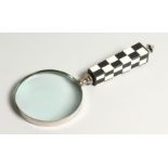 A MAGNIFYING GLASS with a chequered handle.