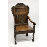 AN 18TH CENTURY OAK ARMCHAIR, with carved cresting rail and panelled back, solid seat and curving