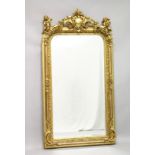 A LARGE DECORATIVE GILT FRAMED MIRROR, the shaped top mounted with cherubs. 5ft 3ins high x 2ft 9ins