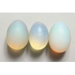 THREE BLUE OPALITE STONES of ovoid form, refracting orange light. Each 2ins long