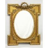 A DECORATIVE GILT FRAMED WALL MIRROR with a shaped rectangular frame and an oval mirror plate. 3ft