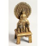A TIBETAN GILT BRONZE SHRINE seated on two figures, the back with caligraaphy. 11ins high.