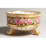 A GOOD CIRCULAR BOWL painted with a band of roses, on three dolphin feet. 6.5ins diameter.