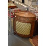 A yew wood bow fronted corner cabinet with a single frieze drawer above a brass grilled door.