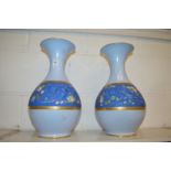 A pair of blue porcelain vases with a band of floral decoration.