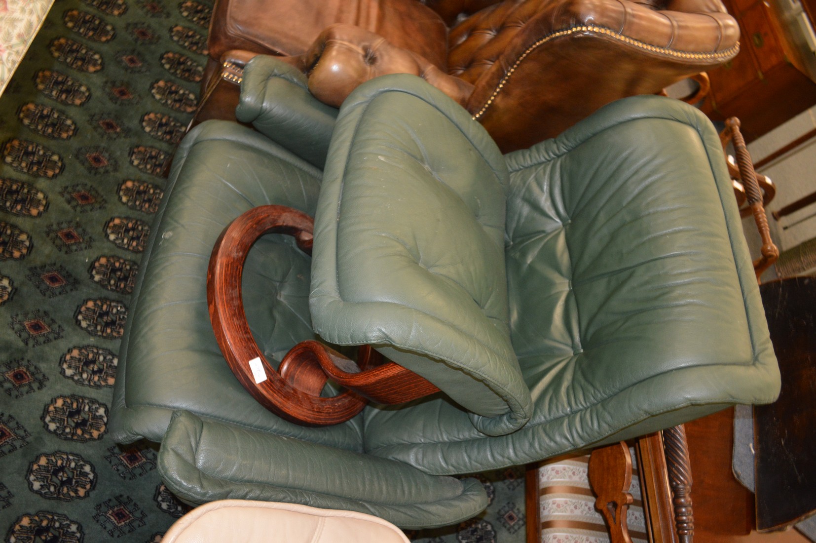 An Ekornes green leather upholstered reclining swivel armchair with matching stool.