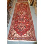 A Persian runner, red ground with stylized decoration.