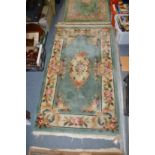 A small green ground floral decorated rug.