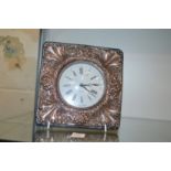 A desk clock with embossed silver frame.