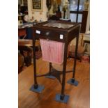 A mahogany sewing table with gallery top, a small drawer and a cloth bag below on square supports.