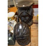 A large carved wood helmet mask and an African stool carved with masks.