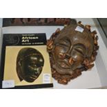 An African pottery mask together with a book on African art.