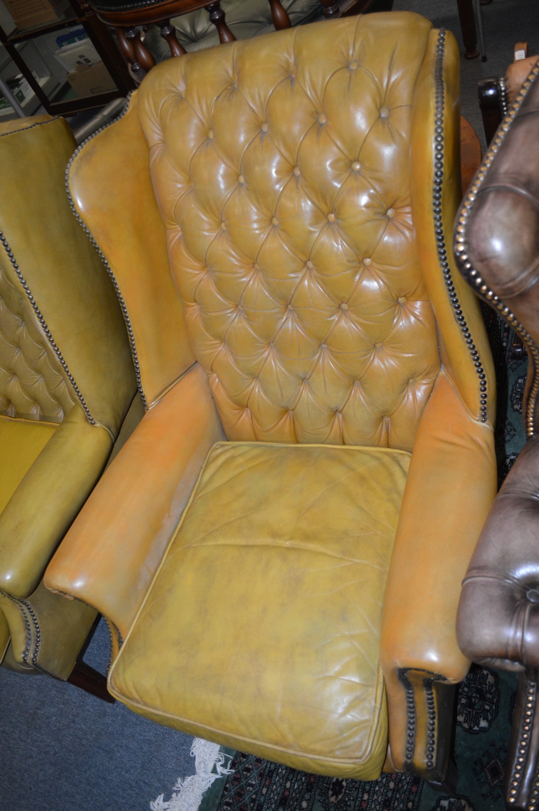 A Georgian style leather button upholstered and brass studded wing armchair.