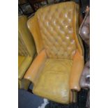 A Georgian style leather button upholstered and brass studded wing armchair.