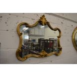 A decorative gilt framed mirror with scrolling frame.