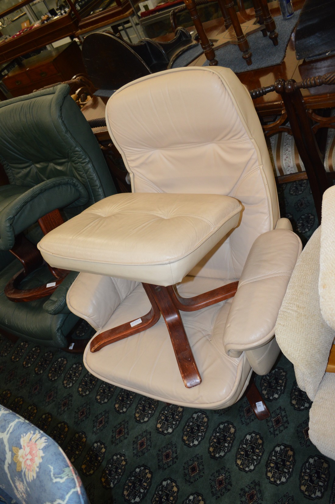 A modern beige leather upholstered reclining revolving armchair with matching stool.