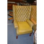 A Georgian style leather button upholstered and brass studded wing armchair.