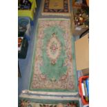 A small floral decorated green ground rug.