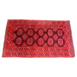 A PERSIAN TEKKE BOKHARA DESIGN RUG, red ground with lozenge shaped medallions. 6ft 6ins x 3ft