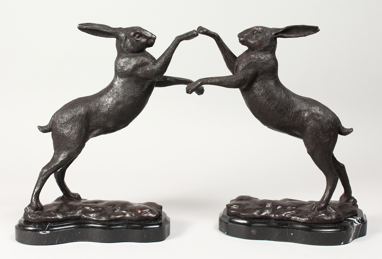 A PAIR OF BRONZE BOXING HARES on shaped marble bases. 11.5ins high.