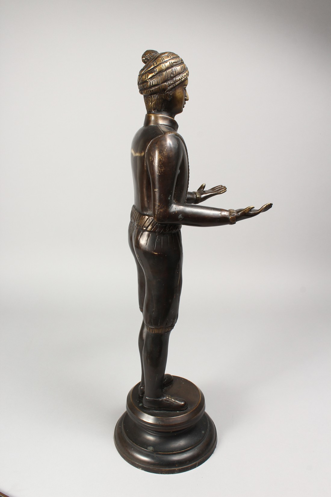 A CAST BRONZE FIGURE OF A STANDING MALE, his arms outstretched, holding a tray, on a circular - Image 3 of 4