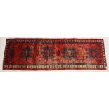 A PERSIAN HERIZ RUNNER, red ground with four large medallions (some wear). 10ft 4ins x 3ft 3ins.