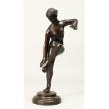 THE ANTIQUE A BRONZE FIGURE OF A STANDING NUDE on one leg, on a circular base. 10ins high.