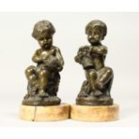 A GOOD PAIR OF EARLY 19TH CENTURY BRONZES OF SEATED PUTTI on circular marble bases. 4ins high