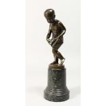 A GOOD BRONZE OF A NUDE YOUNG BOY holding a bag, on a circular marble base. 7.5ins high.