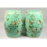 A PAIR OF GREEN CHINESE PORCELAIN BARREL SEATS with flowers and birds. 17.5ins high.