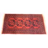 A PERSIAN TEKKE DESIGN RUG, red ground with four large central medallions. 6ft 2ins x 3ft 5ins.